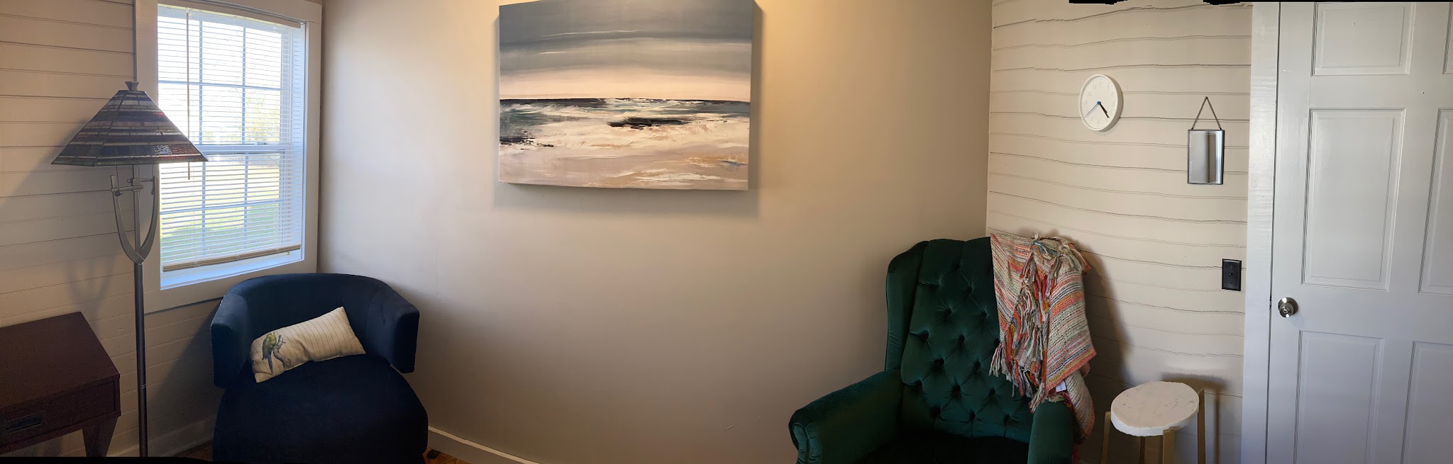 A private counseling room at ThisLife Counseling with comfortable blue and green chairs, soft lighting, and coastal artwork